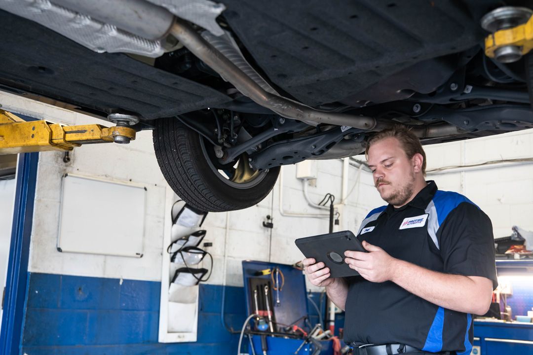 Technician Inspecting Vehicle Undercarriage With Tablet | Protime Automotive