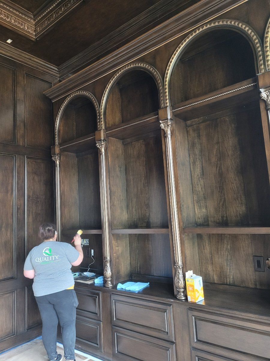 A woman is cleaning shelves in a room.