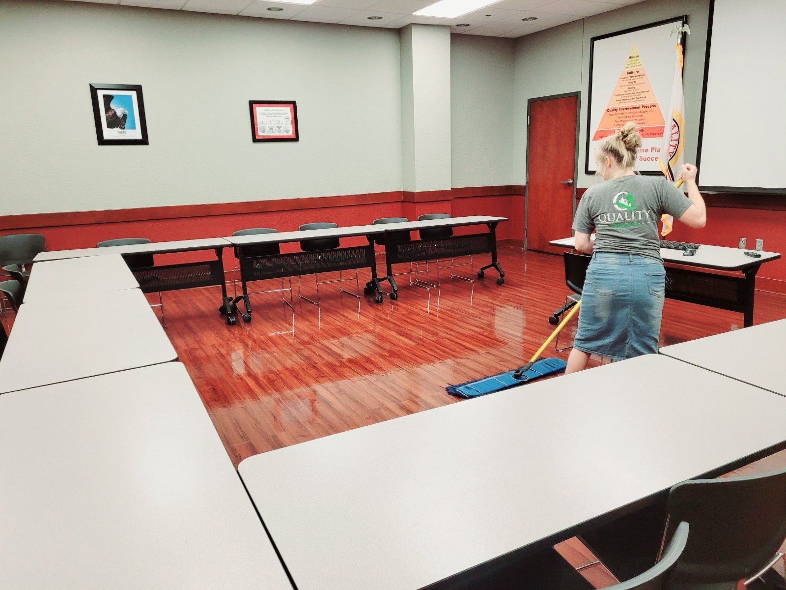 A woman is cleaning a classroom with a mop.