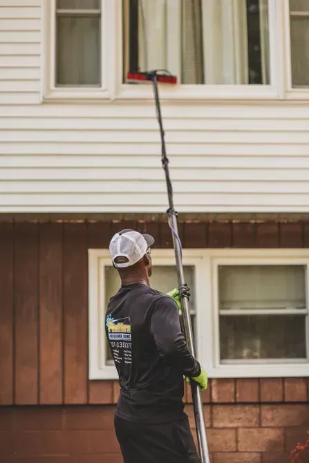 A man is cleaning a window on the side of a house.