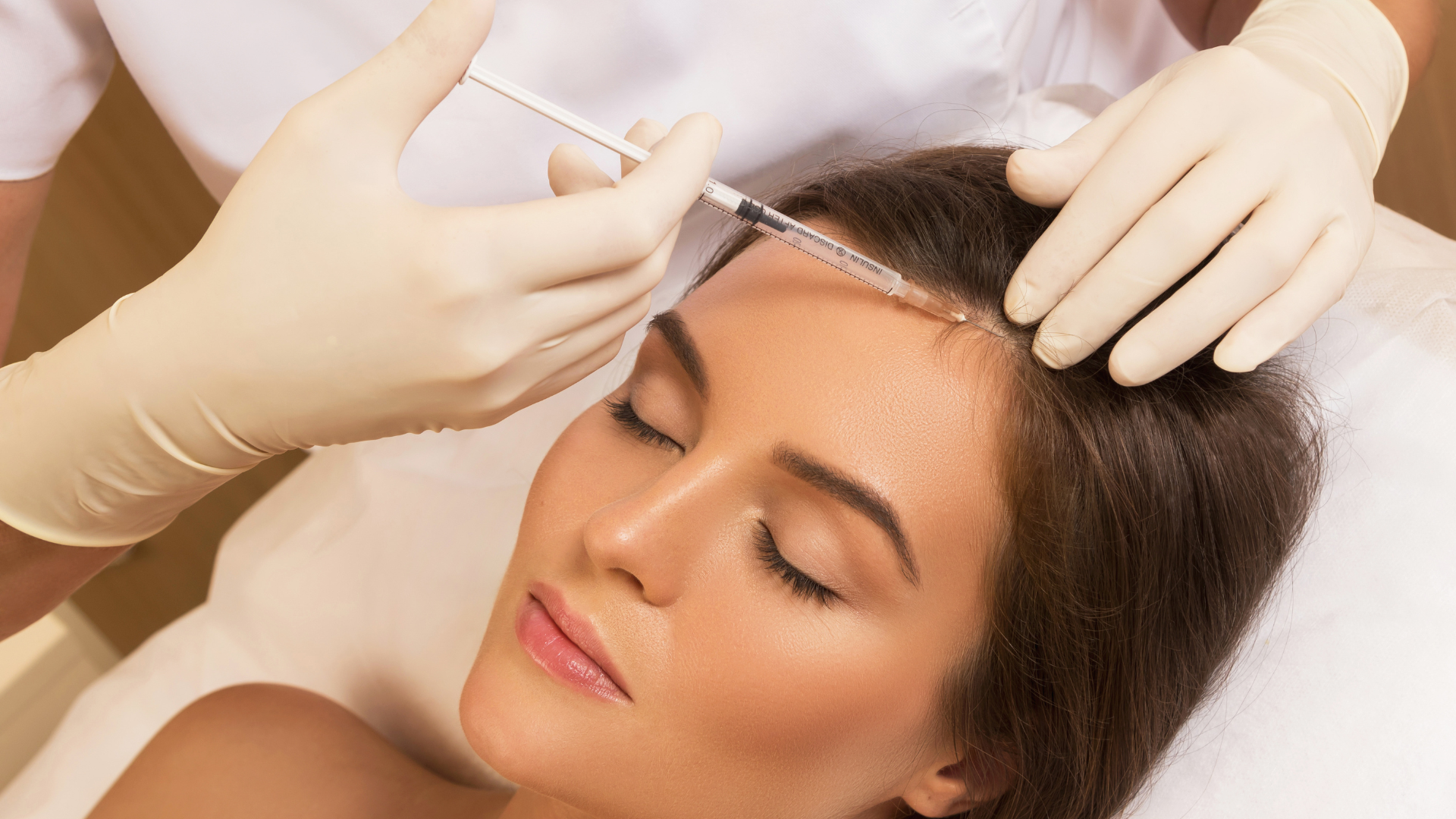 A woman is getting a botox injection in her forehead.