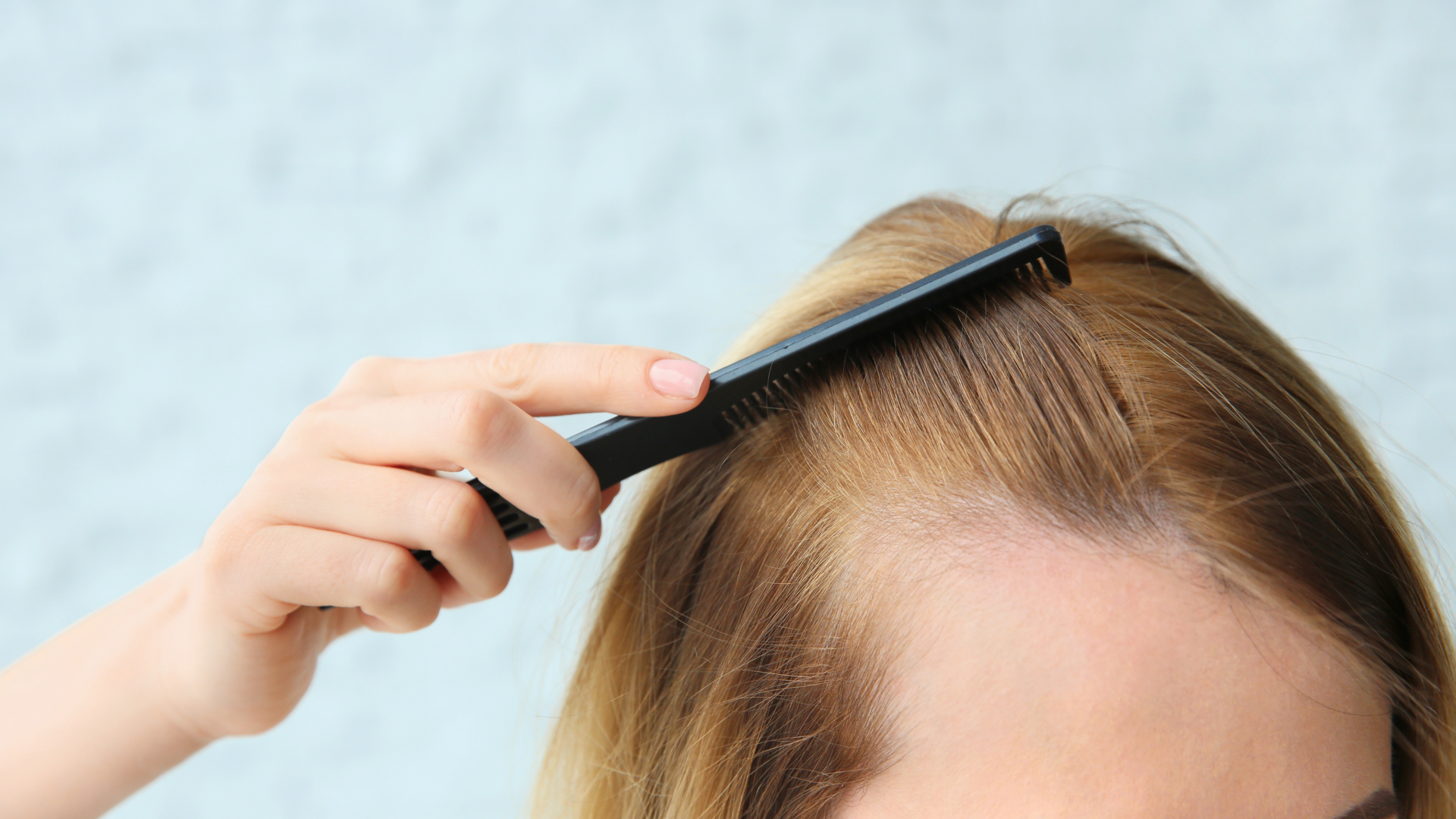 A woman is combing her hair with a comb.