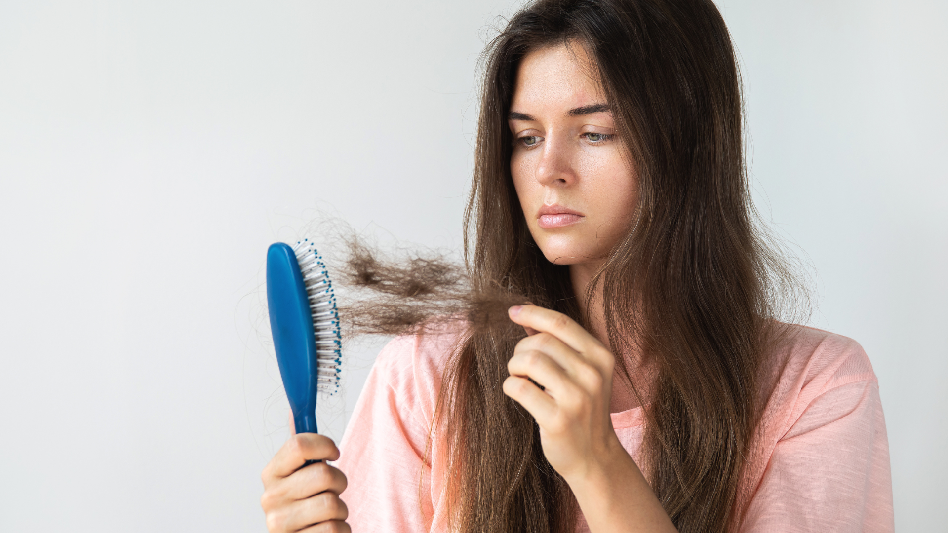A woman is brushing her hair with a blue brush.