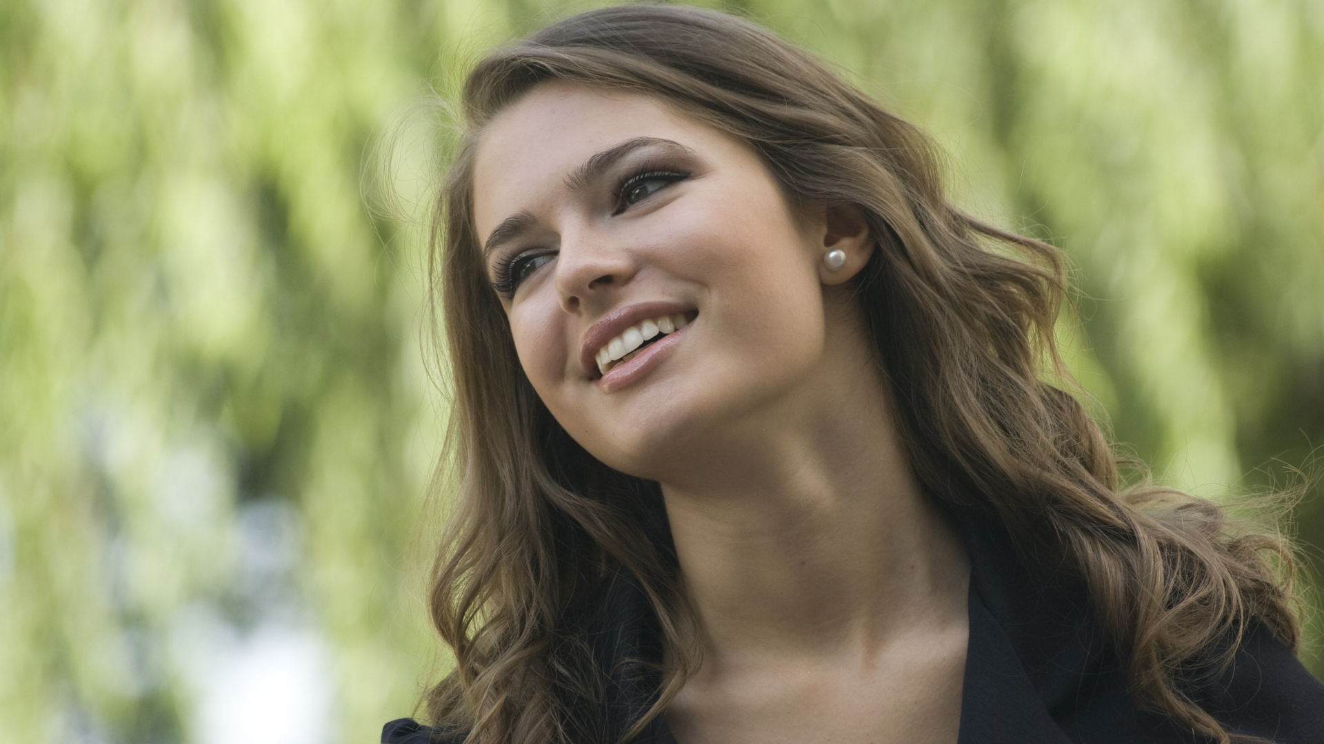 A woman with long hair is smiling and looking up.