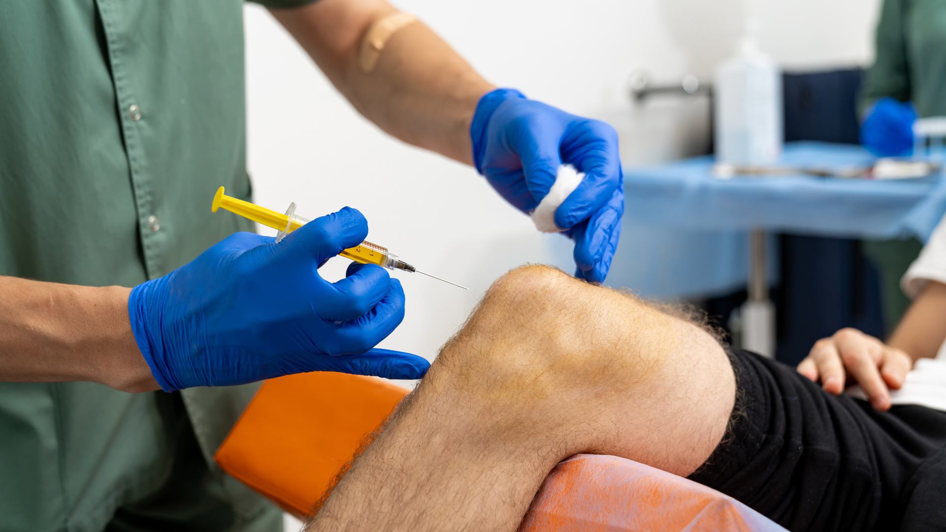 A doctor is giving a patient an injection in their knee.
