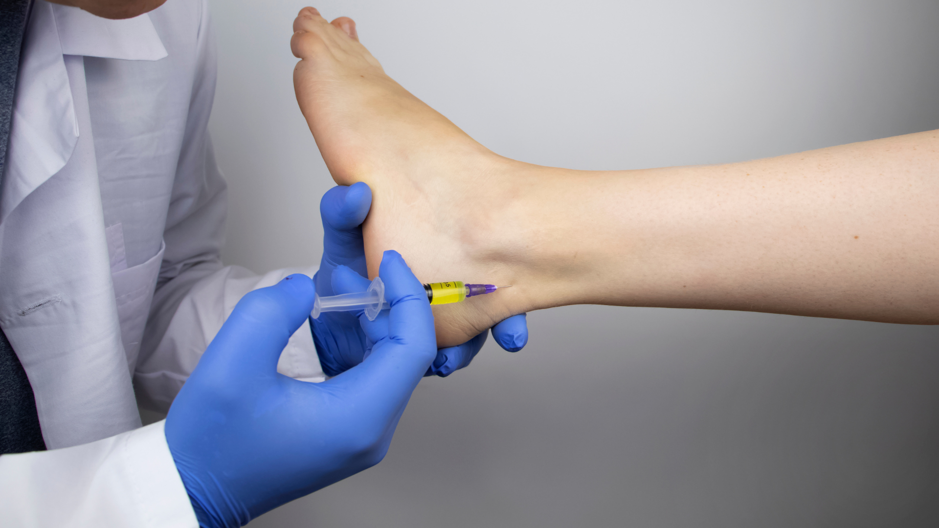 A doctor is giving a patient an injection in their foot.
