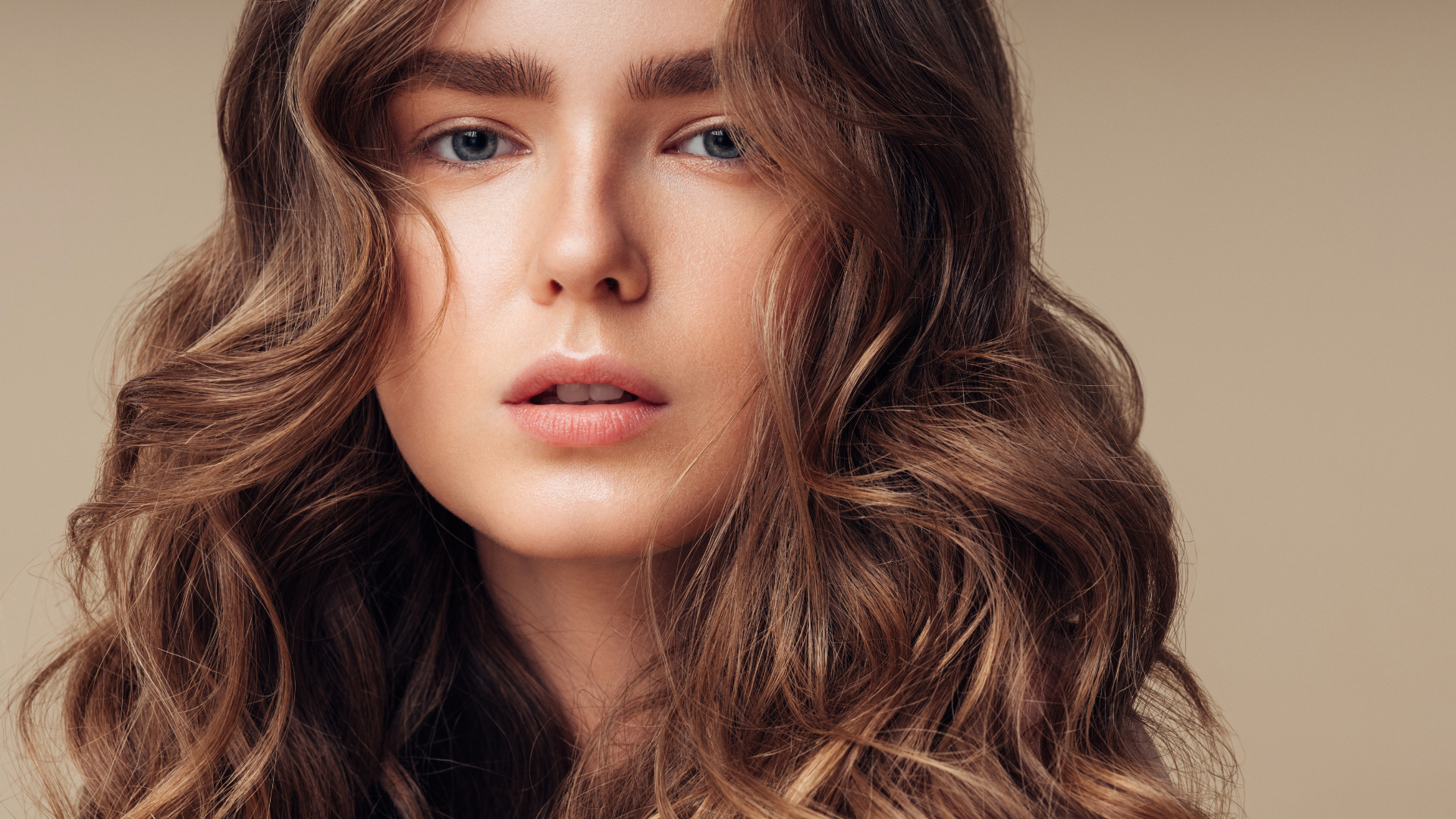 A woman with long curly hair is looking at the camera.