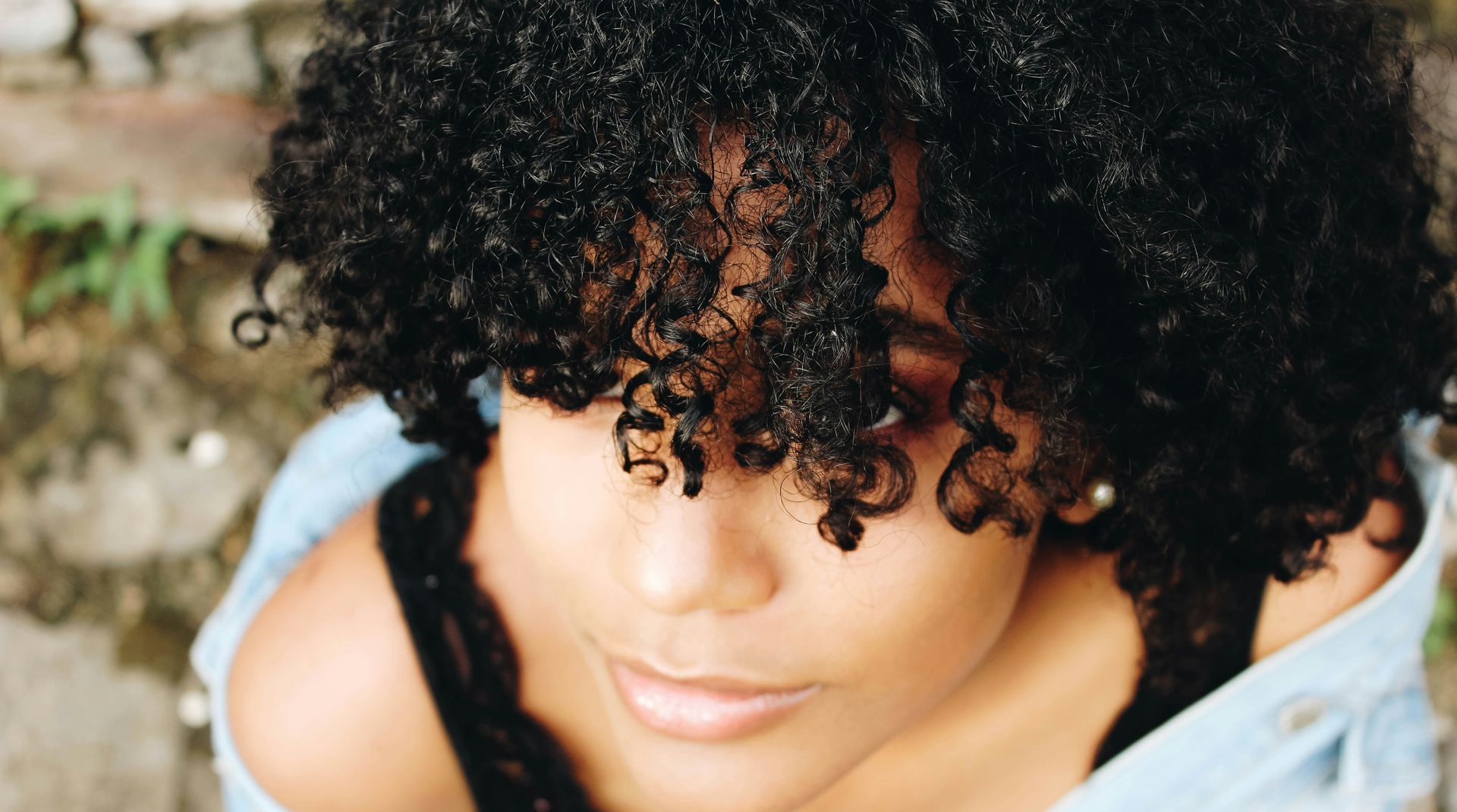 A close up of a woman with curly hair looking down.