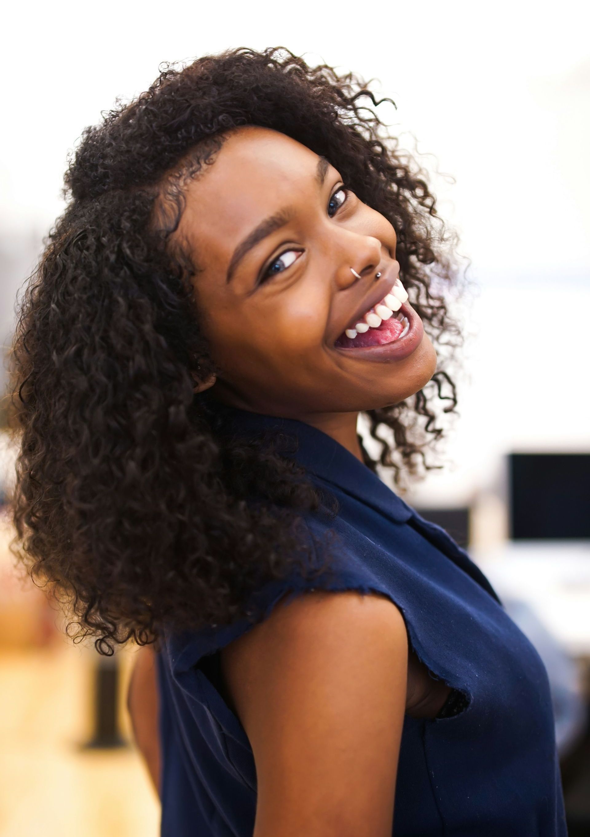 A woman with curly hair is smiling and looking at the camera.