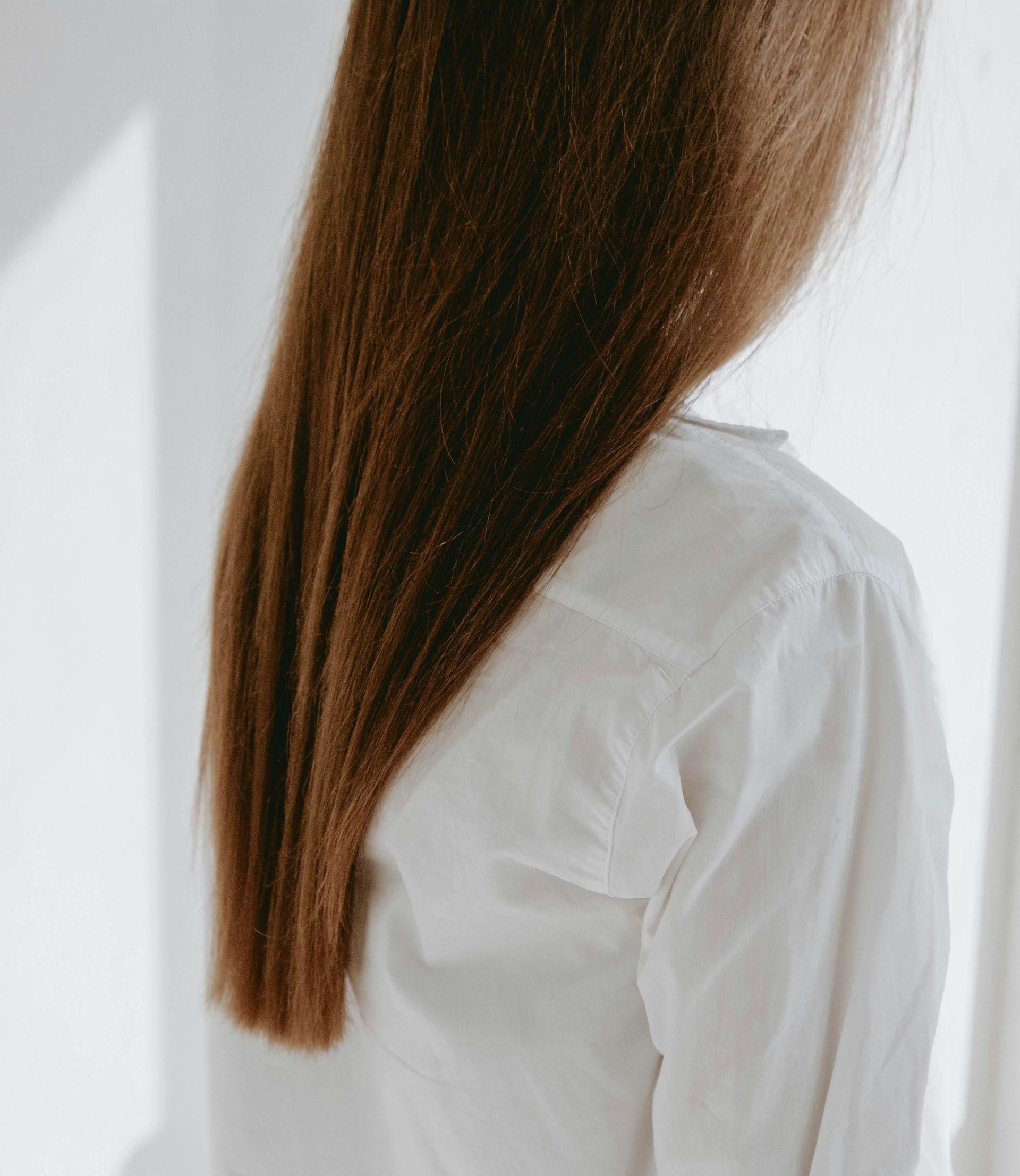 A woman with long brown hair is wearing a white shirt.