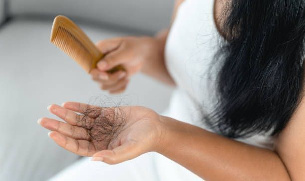 A woman is brushing her hair with a wooden comb.
