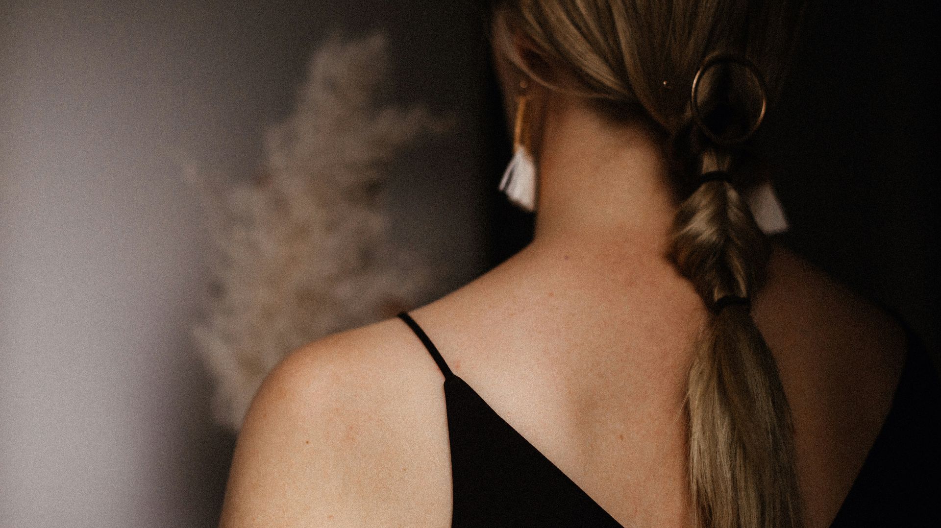 The back of a woman wearing a black dress and a braided ponytail.