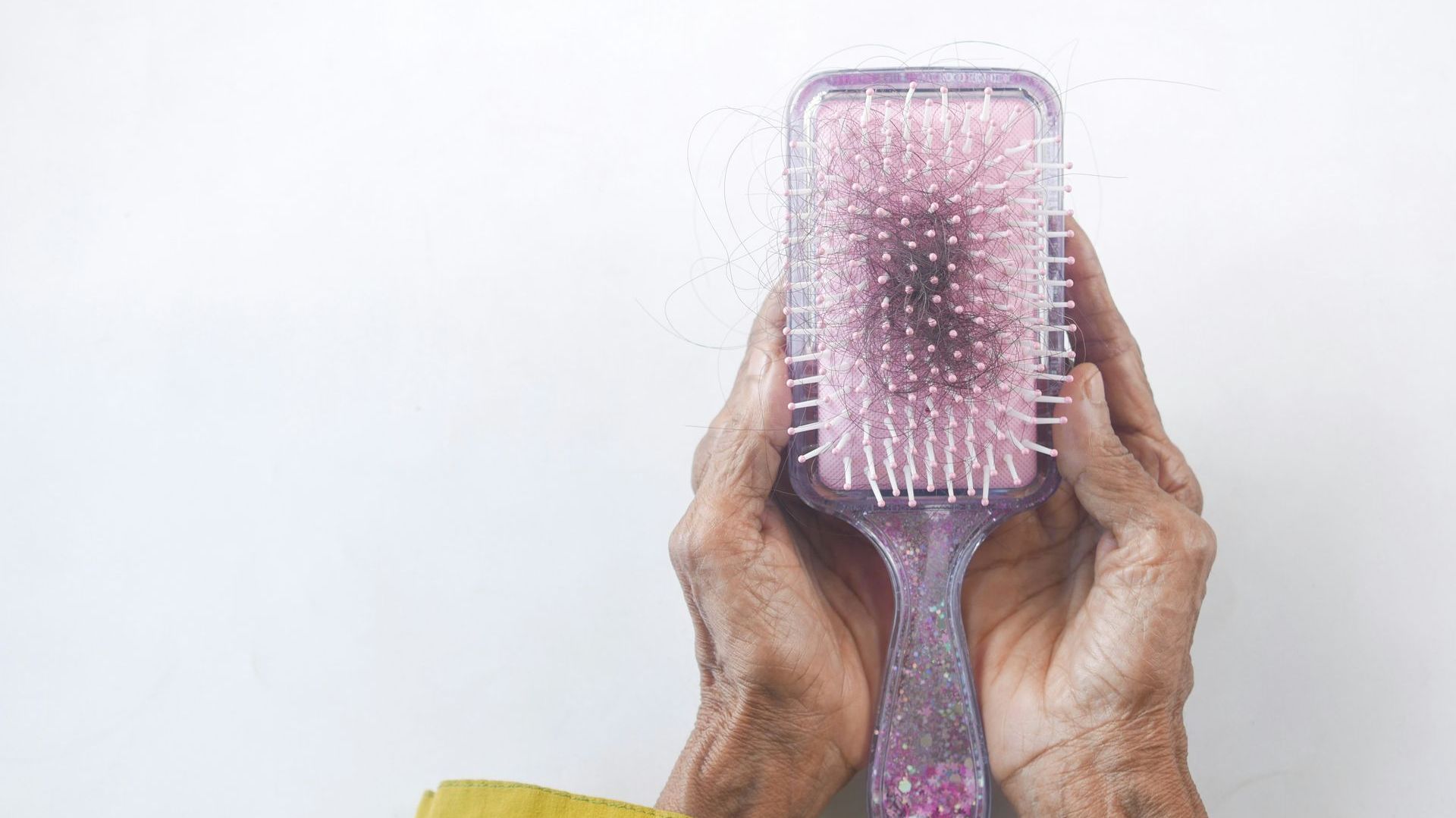 A person is holding a purple hair brush in their hands.