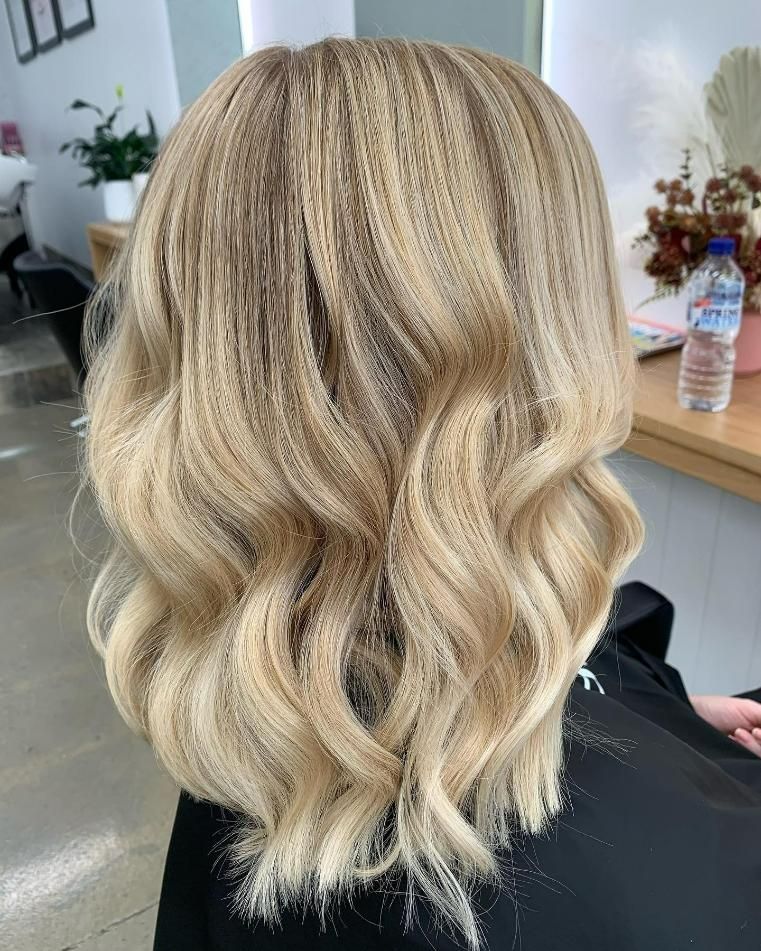 A Woman with Blonde Hair Is Sitting in A Chair in A Salon — Eden Hair in Pacific Paradise, QLD
