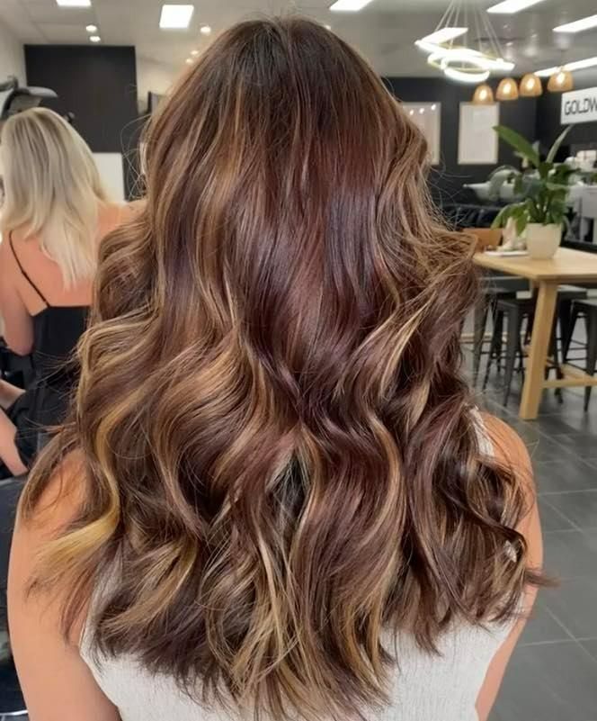 A Woman with Long Brown Hair Is Sitting in A Salon — Eden Hair in Pacific Paradise, QLD