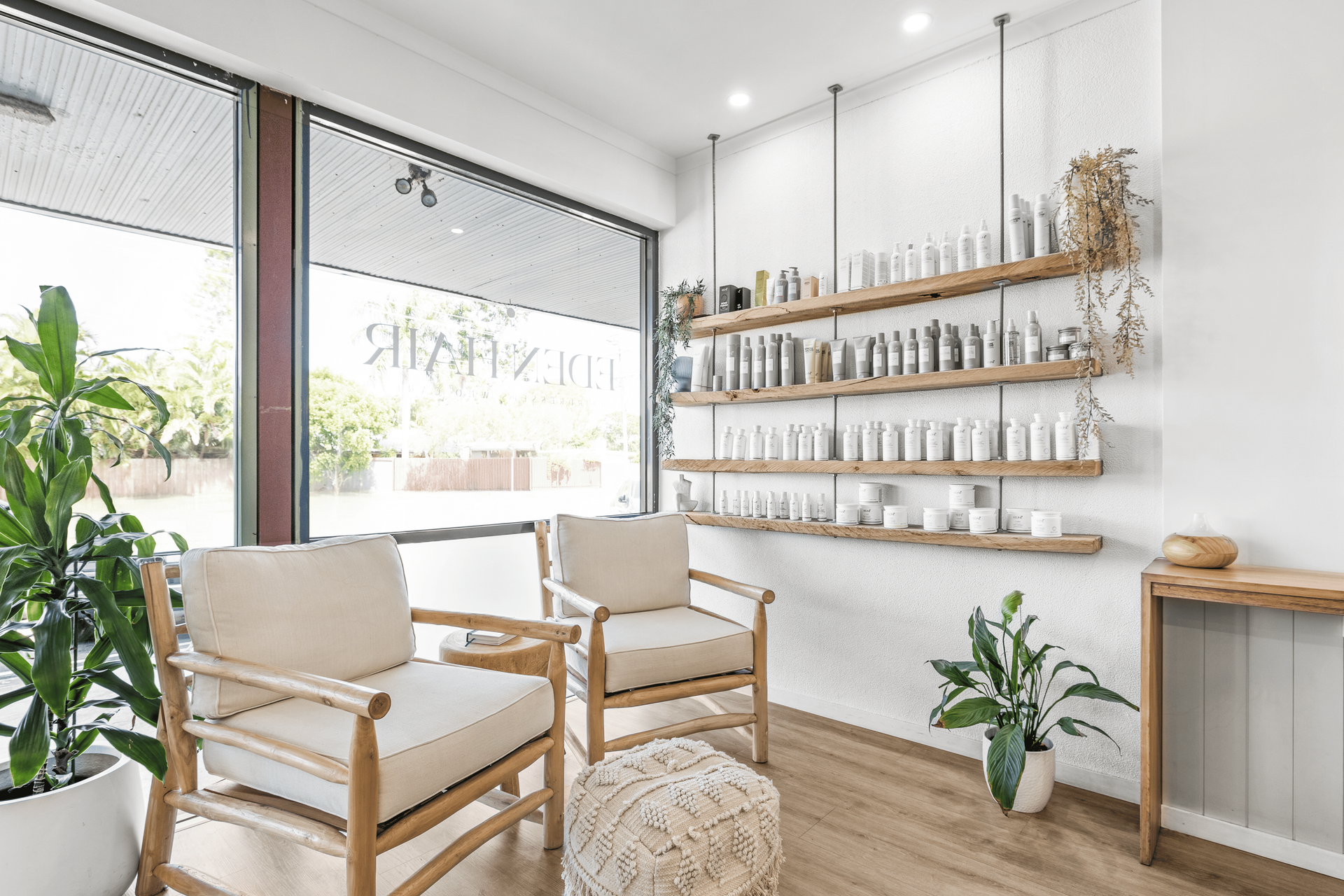 Salon interior with two armchairs, shelving with products, and large window — Eden Hair in Pacific Paradise, QLD