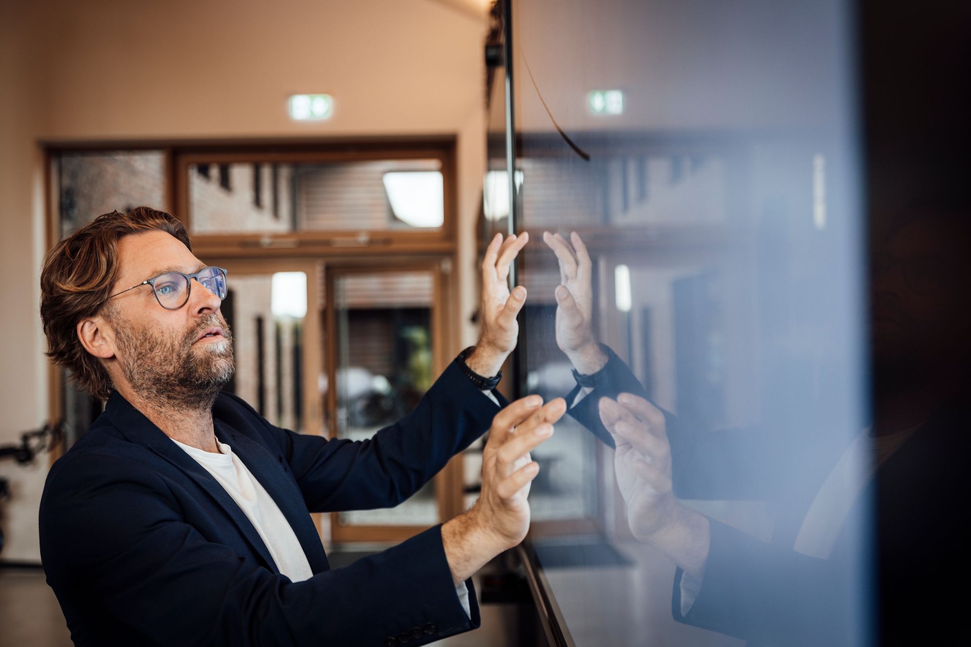 Businessman using big touch screen in modern office meeting room.