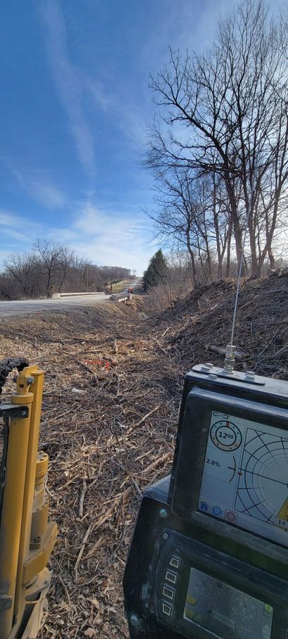 A clear sky with leafless trees borders a rugged dirt path with electronic devices on the right.