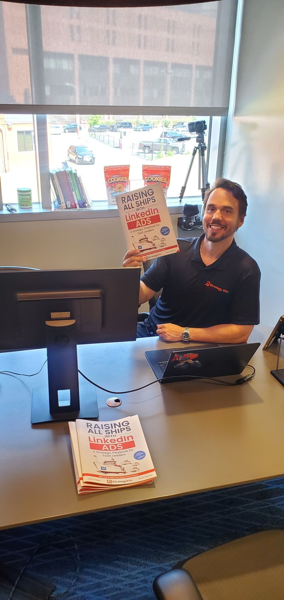 Adam Fischer at Strategy Kiln’s Providence office, holding a LinkedIn Ads book