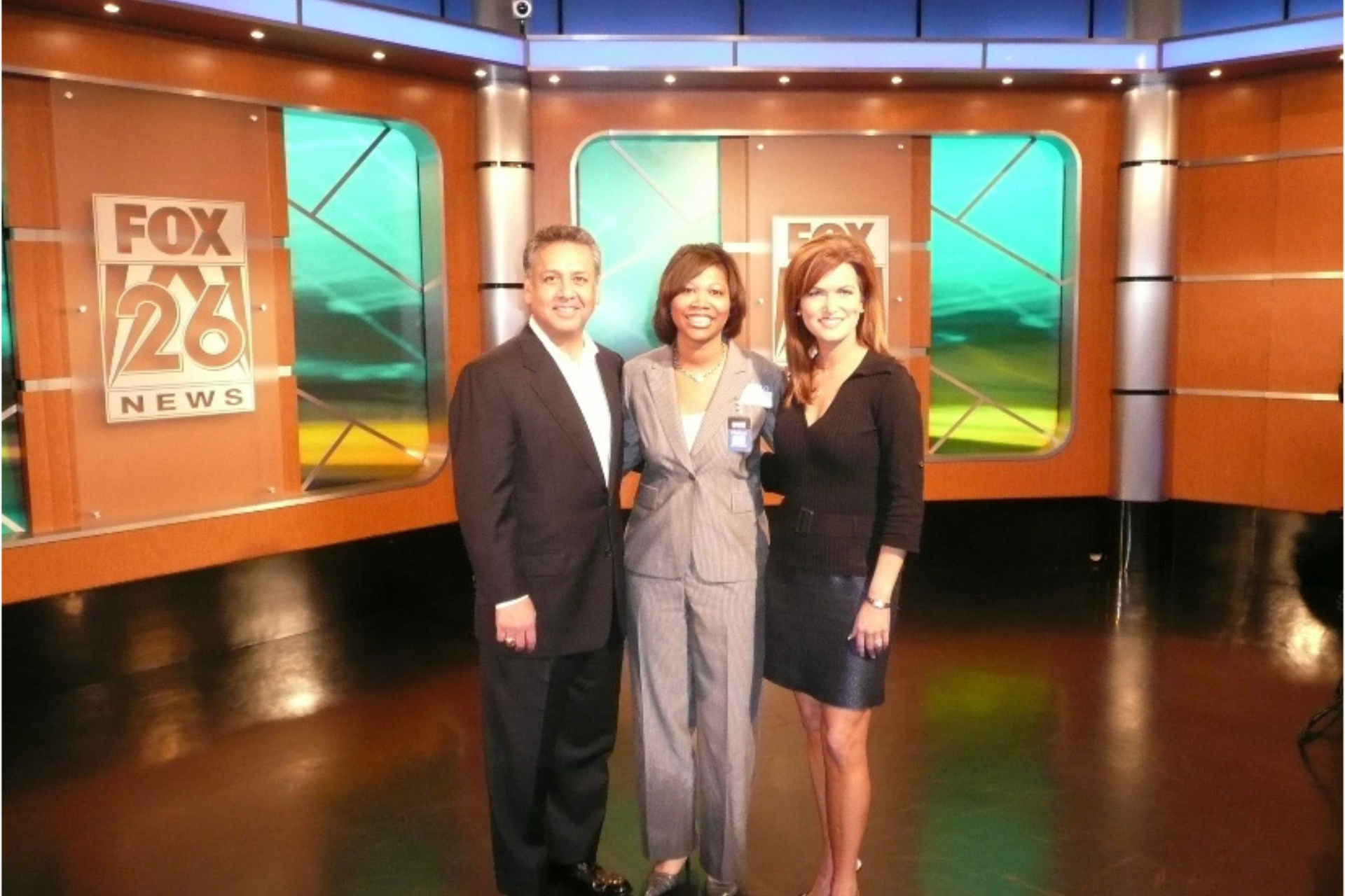 Courtney and Fox 28 News team posing in the studio with a wood-paneled set and green screens.