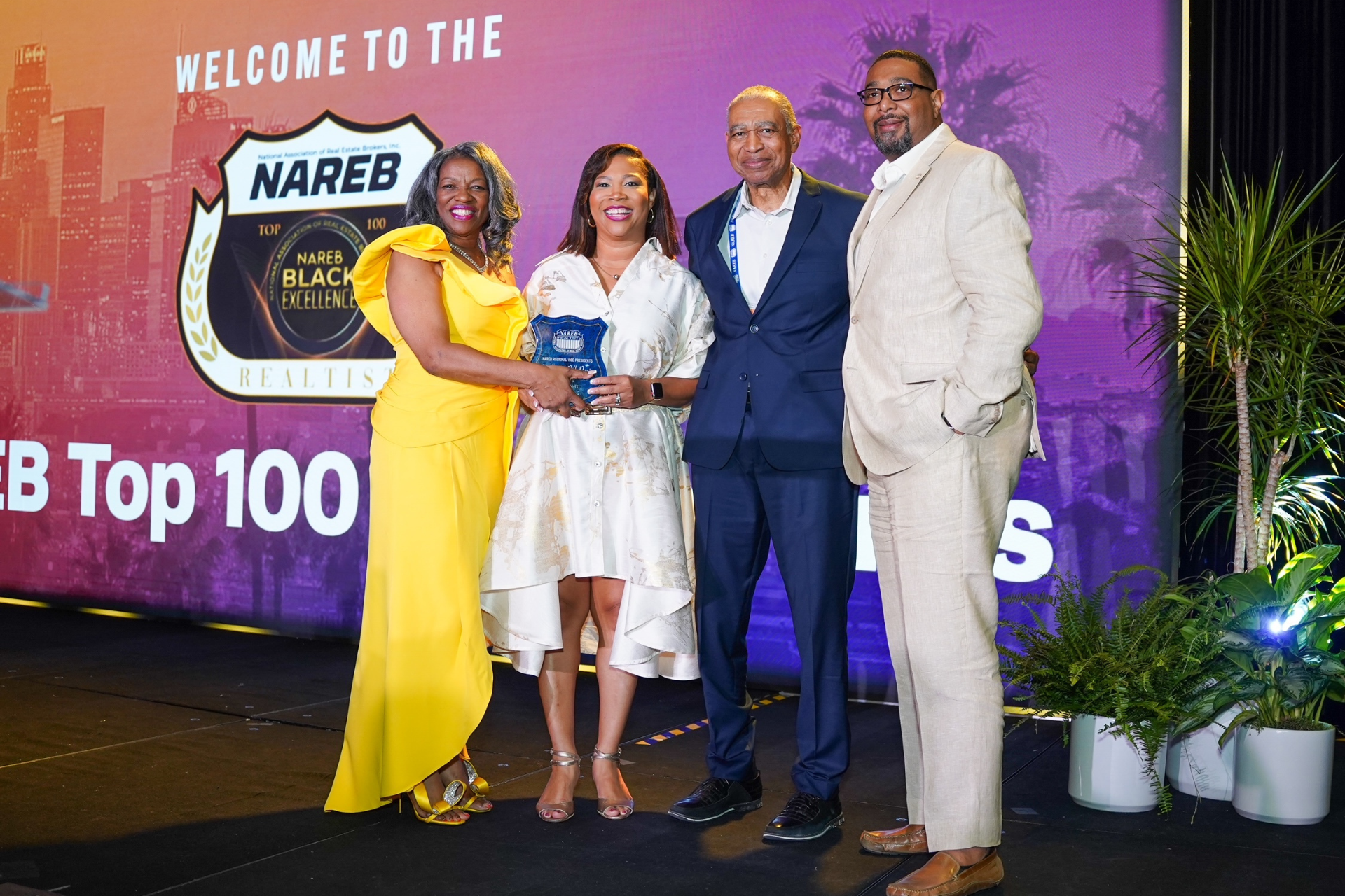 Courtney and colleagues posing on a red carpet at a NABE Top 100 event backdrop, dressed in formal attire.