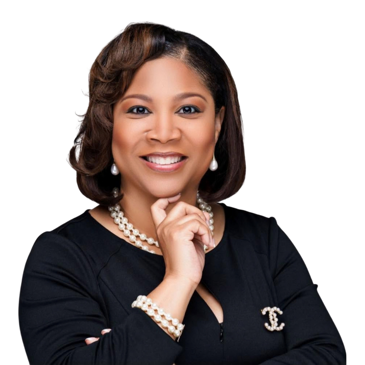 Courtney Johnson Rose smiling in a black blazer with pearl jewelry, posed against a white background
