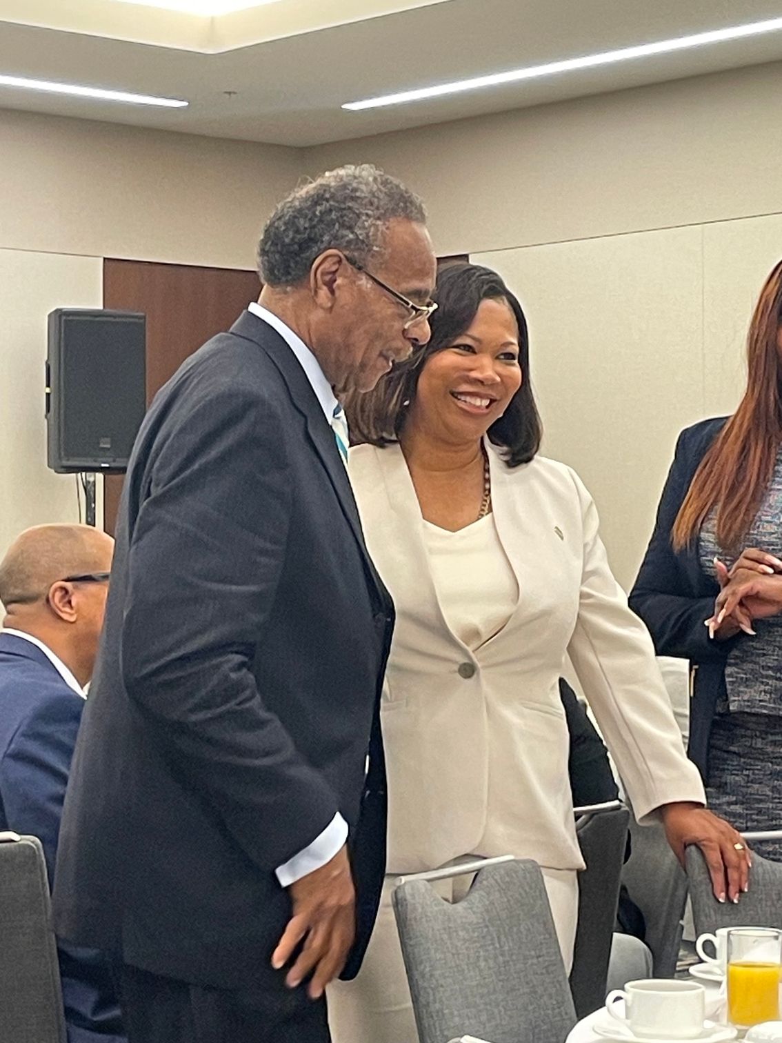 Courtney is smiling with a colleague and talking at a conference table in a meeting room