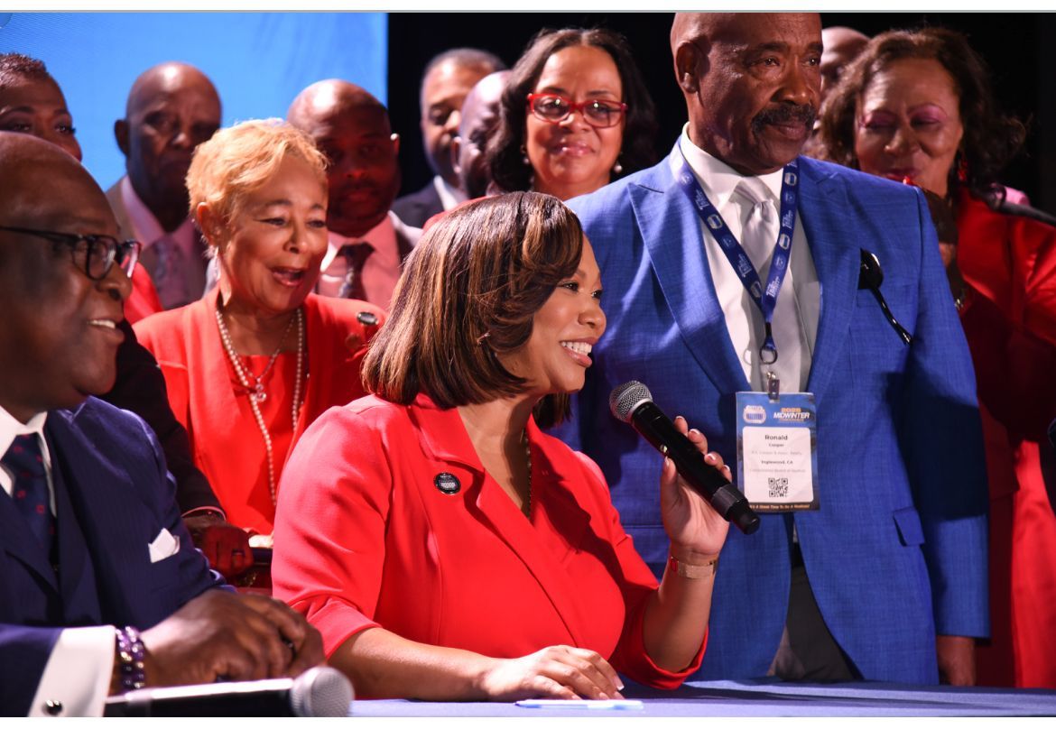 Courtney is speaking at a conference panel in a red jacket.