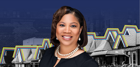 Courtney in a black top and pearls before a blue backdrop with a bridge and geometric building pattern