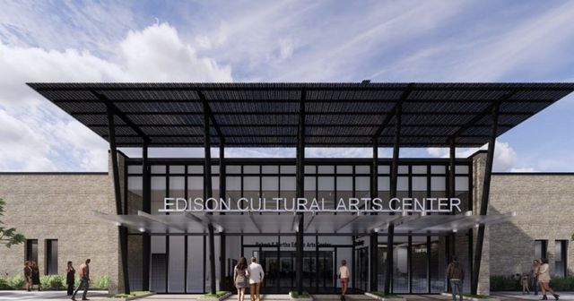 Modern glass-fronted cultural arts center with a large canopy entrance and a few people outside