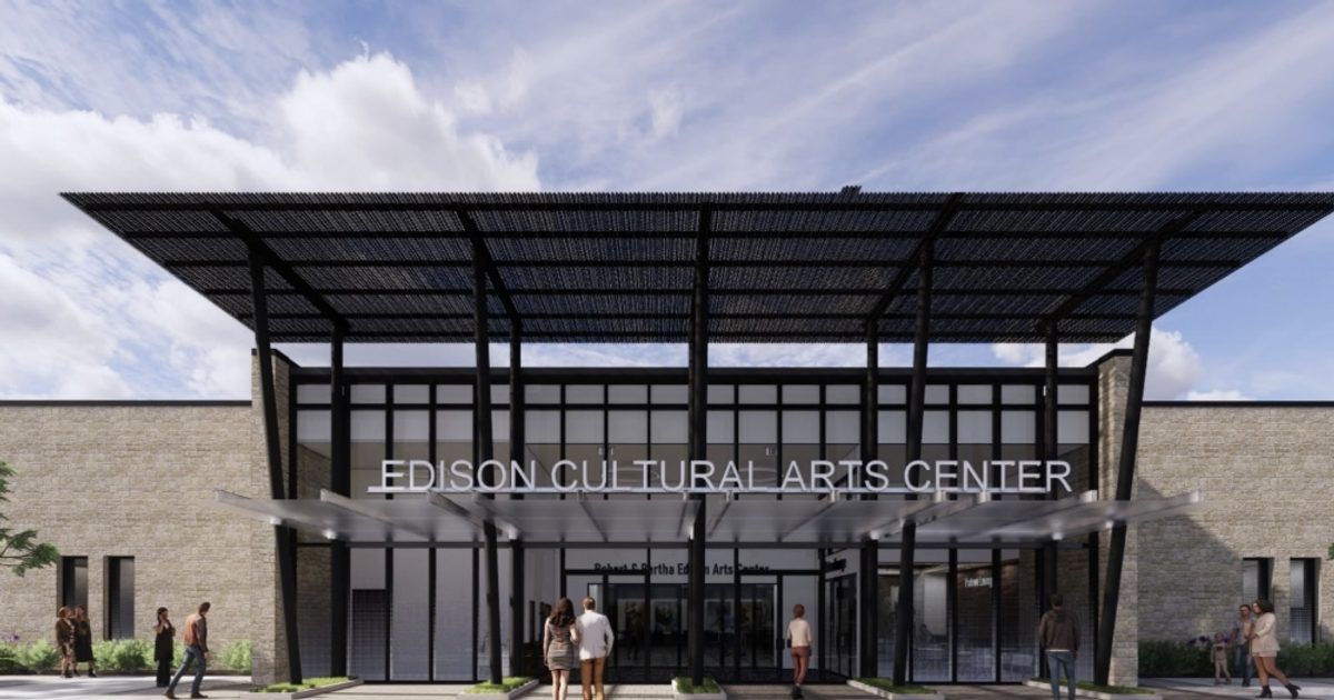 Modern glass-and-steel arts center entrance with a large canopy and people standing outside