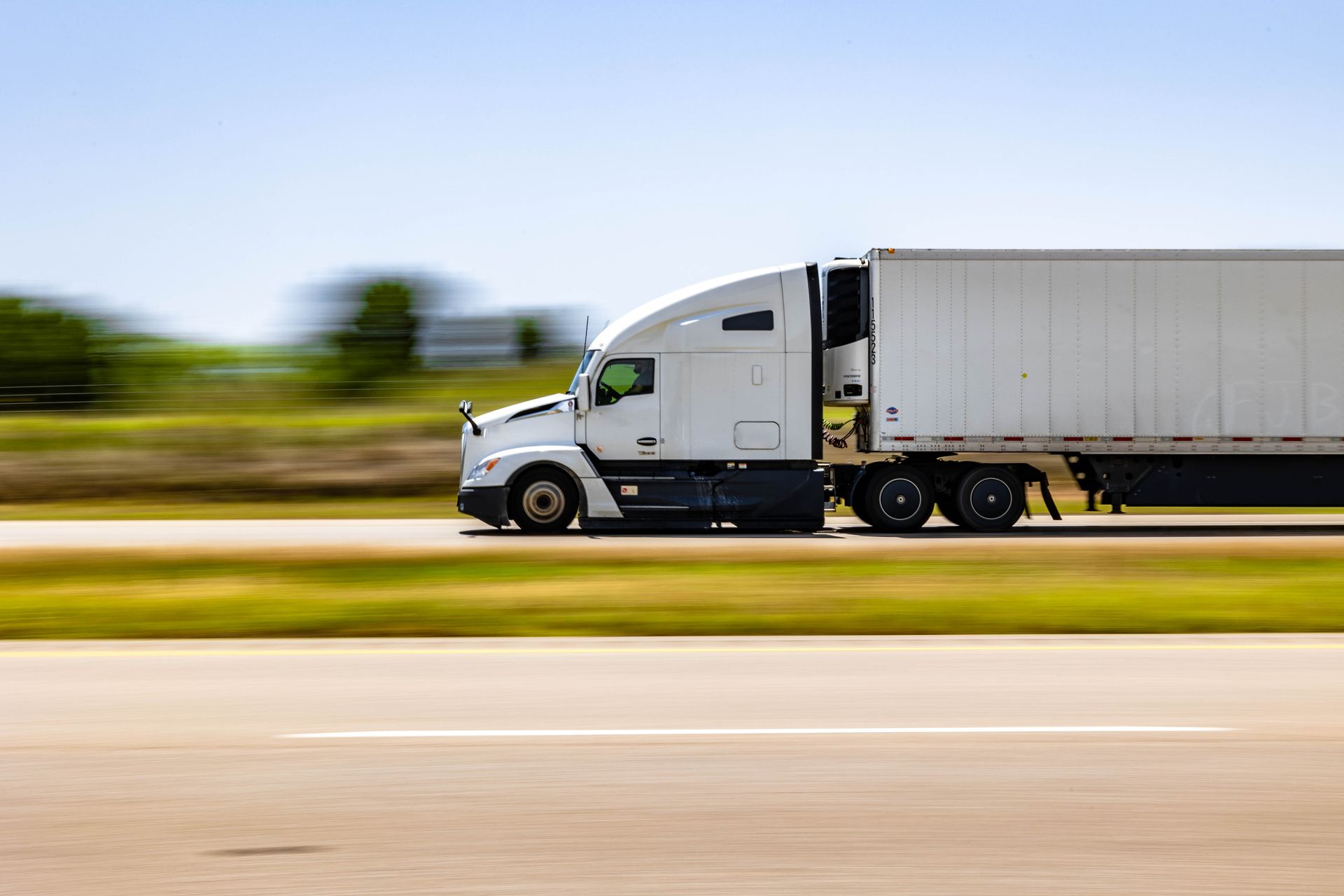 A white semi truck is driving down a highway.