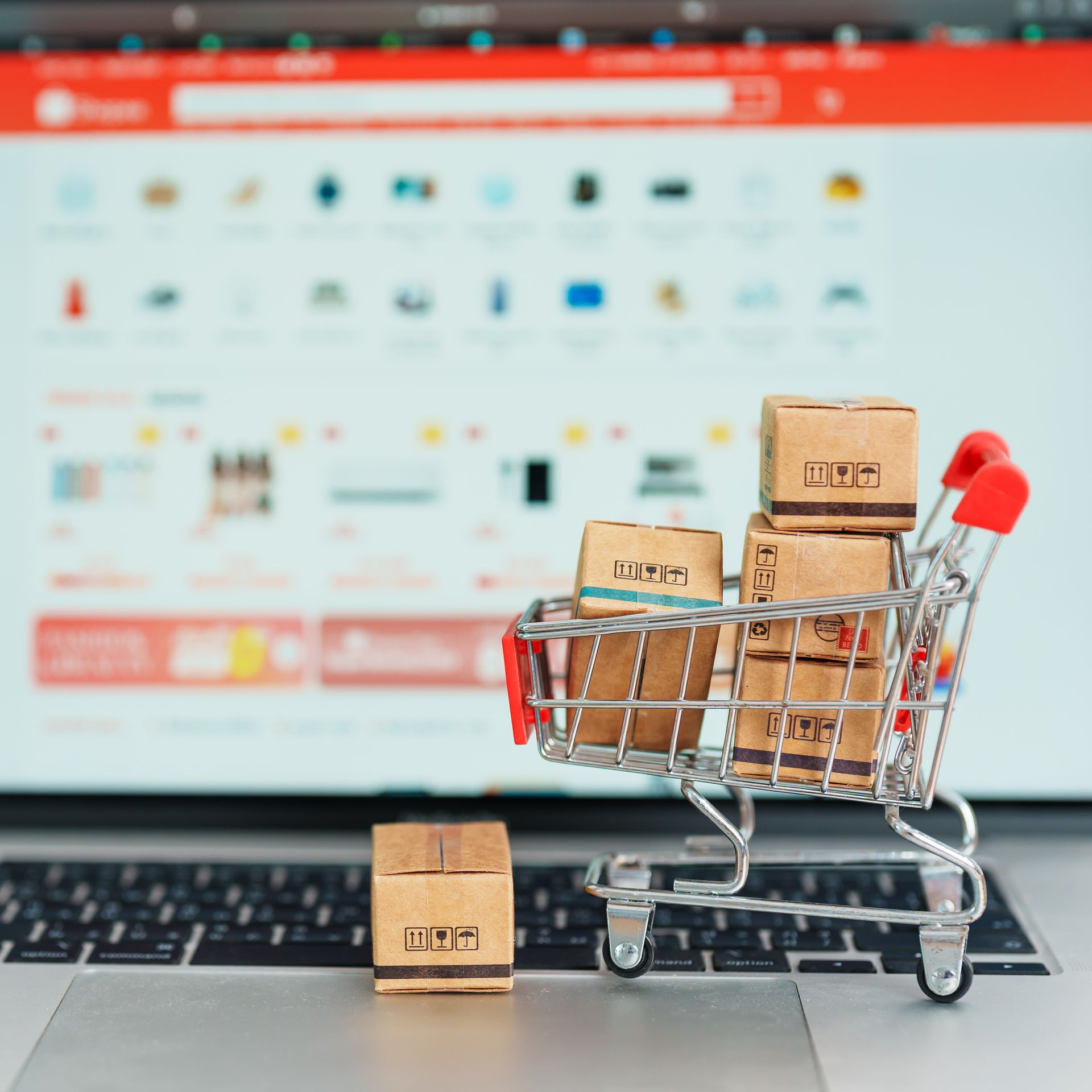 A shopping cart with boxes in it is on a laptop keyboard.