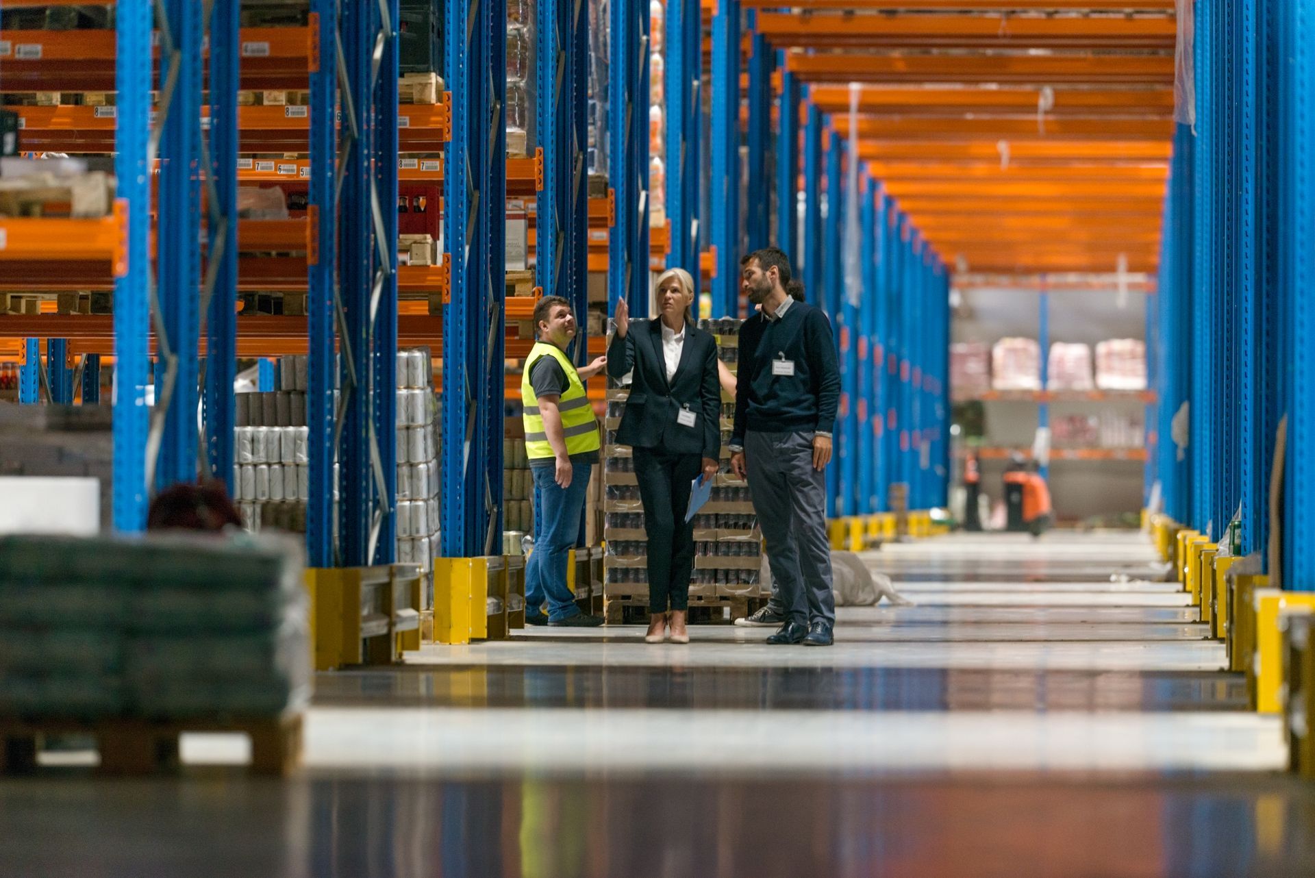 A group of people are standing in a warehouse talking to each other.
