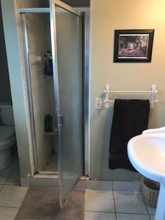 Bathroom with shower, sink, toilet, towel rack, and framed picture on a light green wall.