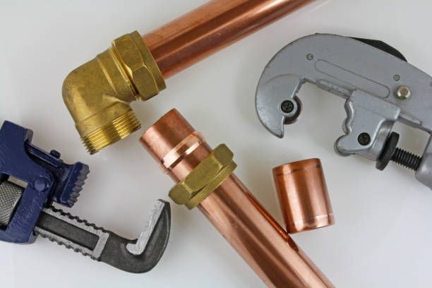 Copper plumbing fittings and tools on a white surface.