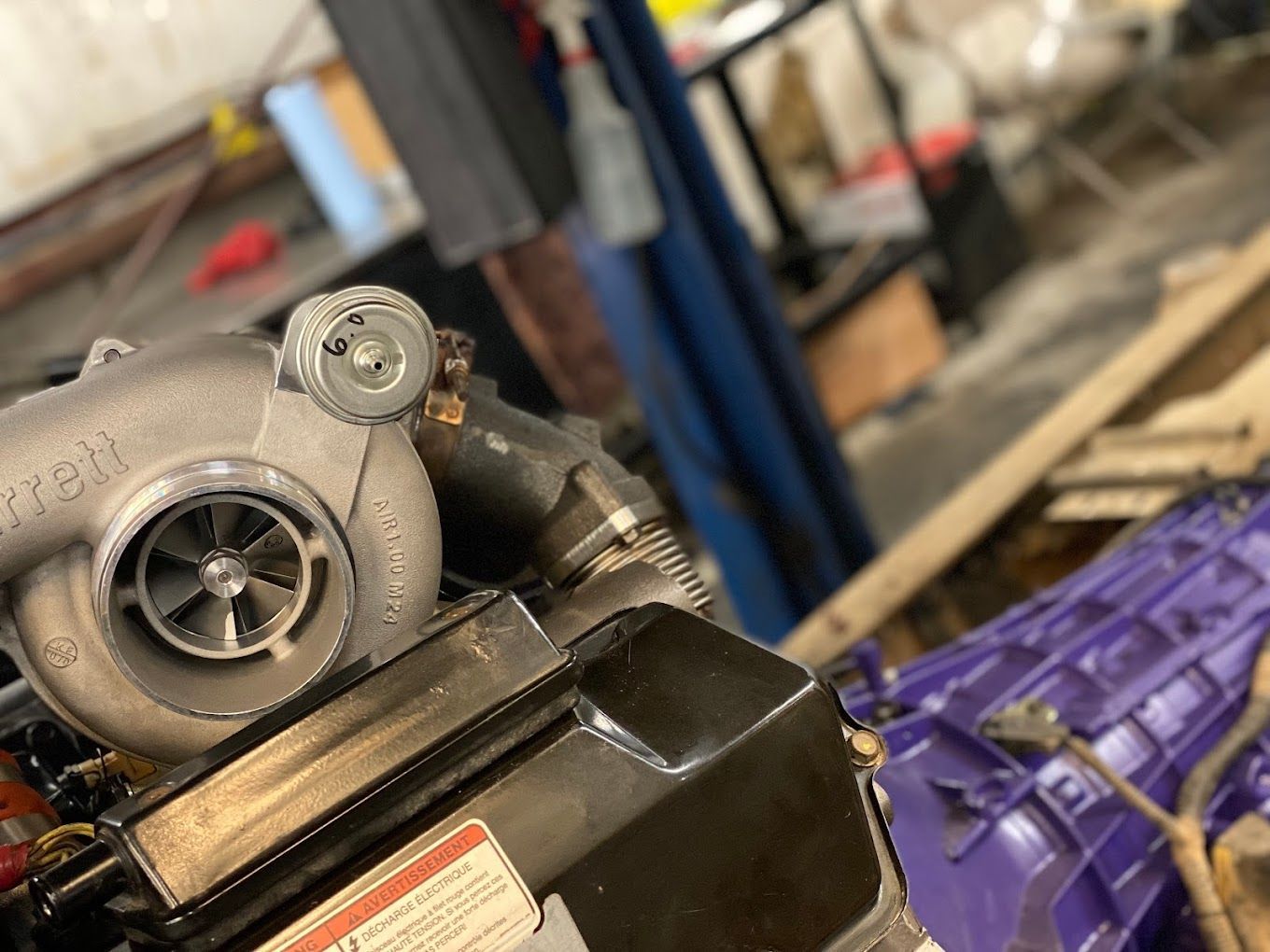 a turbocharger is sitting on top of a purple gearbox in a garage .