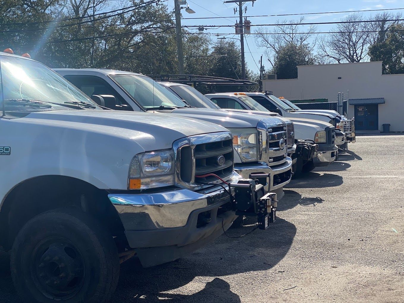 a row of white trucks are parked in a parking lot .