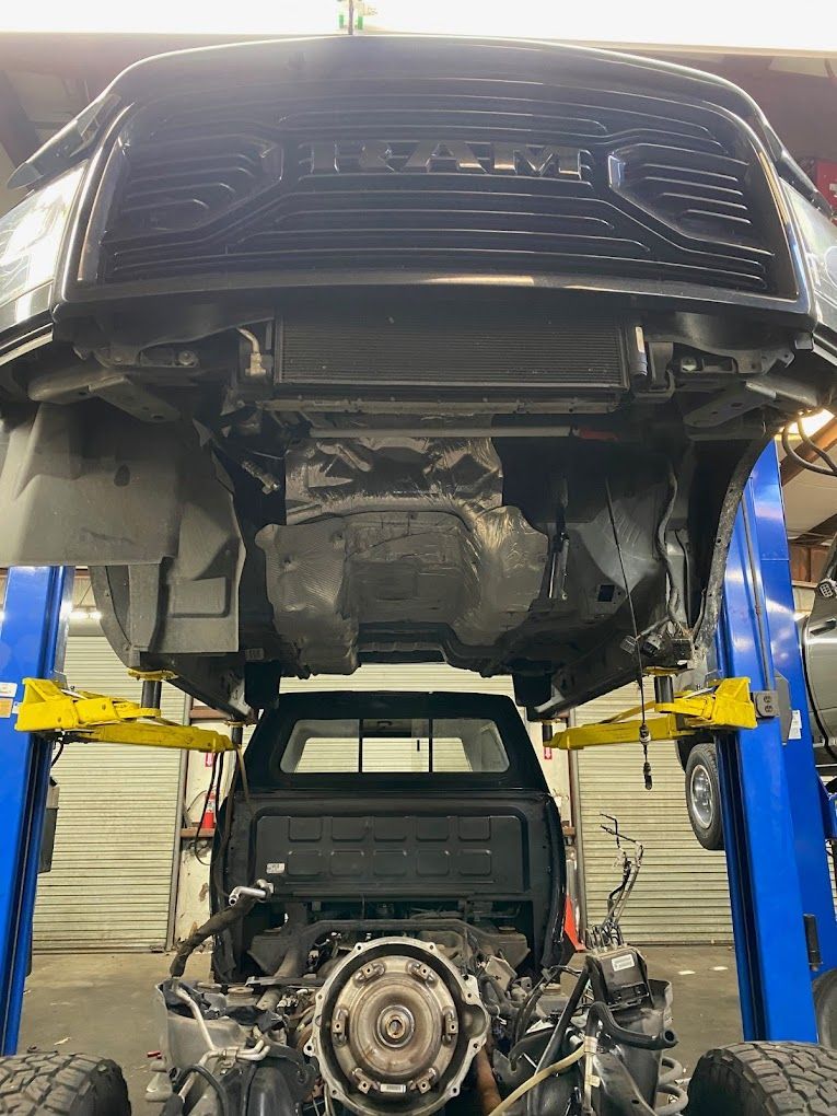 a truck with the hood up is on a lift in a garage .