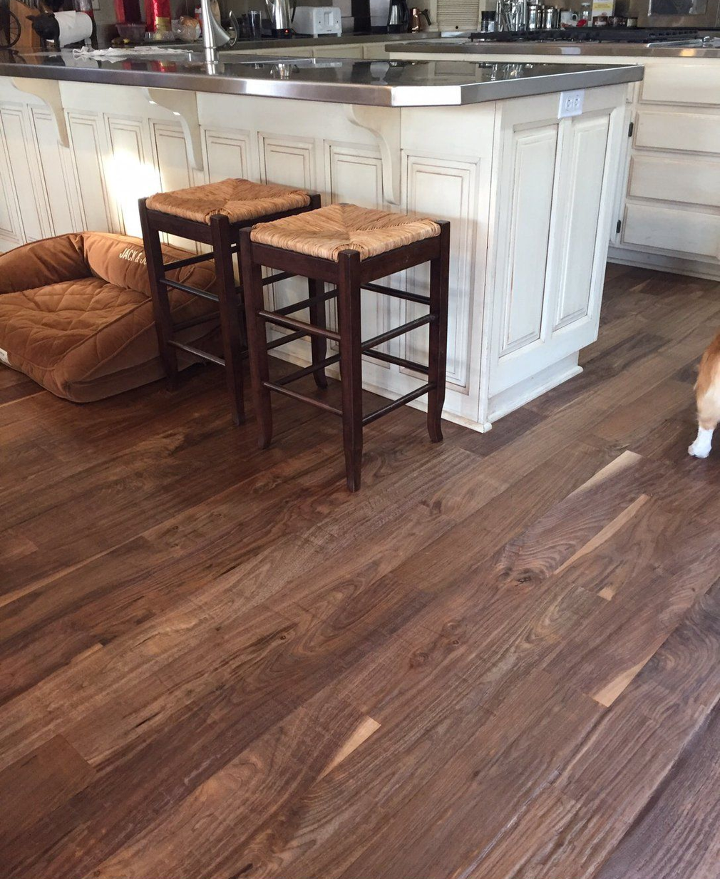 Kitchen island with two wooden stools on a dark wood floor, with a brown dog bed nearby.