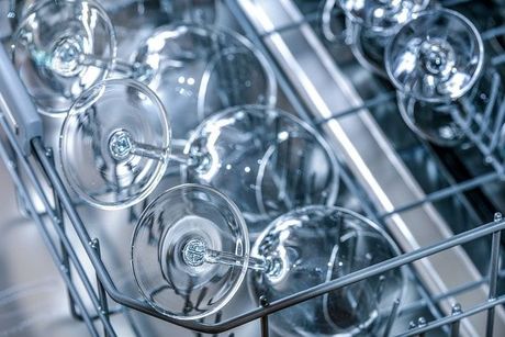 A close up of wine glasses in a dishwasher.