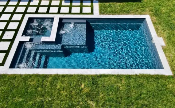 A small swimming pool is sitting in the middle of a lush green lawn.