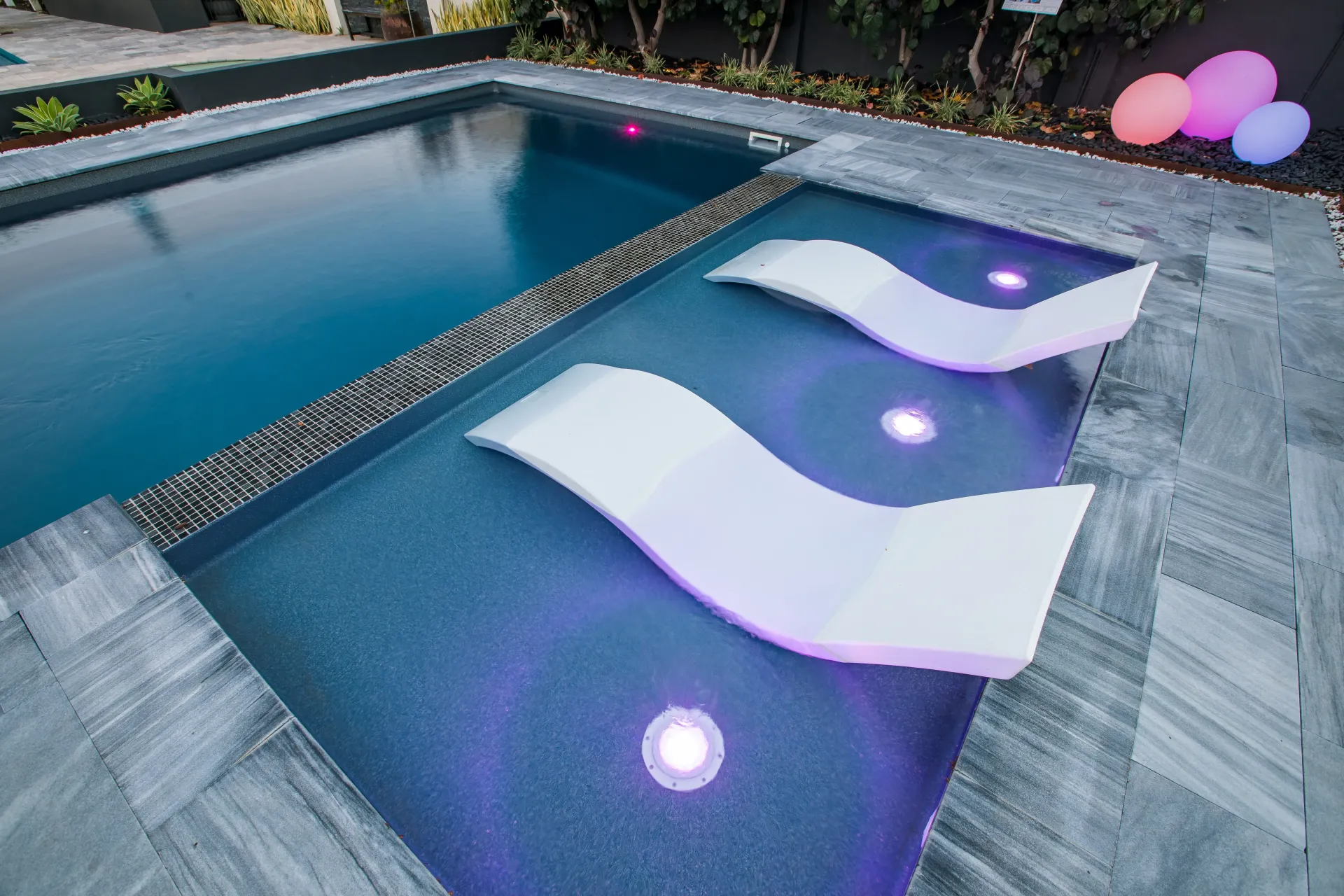 Modern plunge pool with in-pool loungers and LED lighting, featuring sleek tile decking and luxury poolside design.