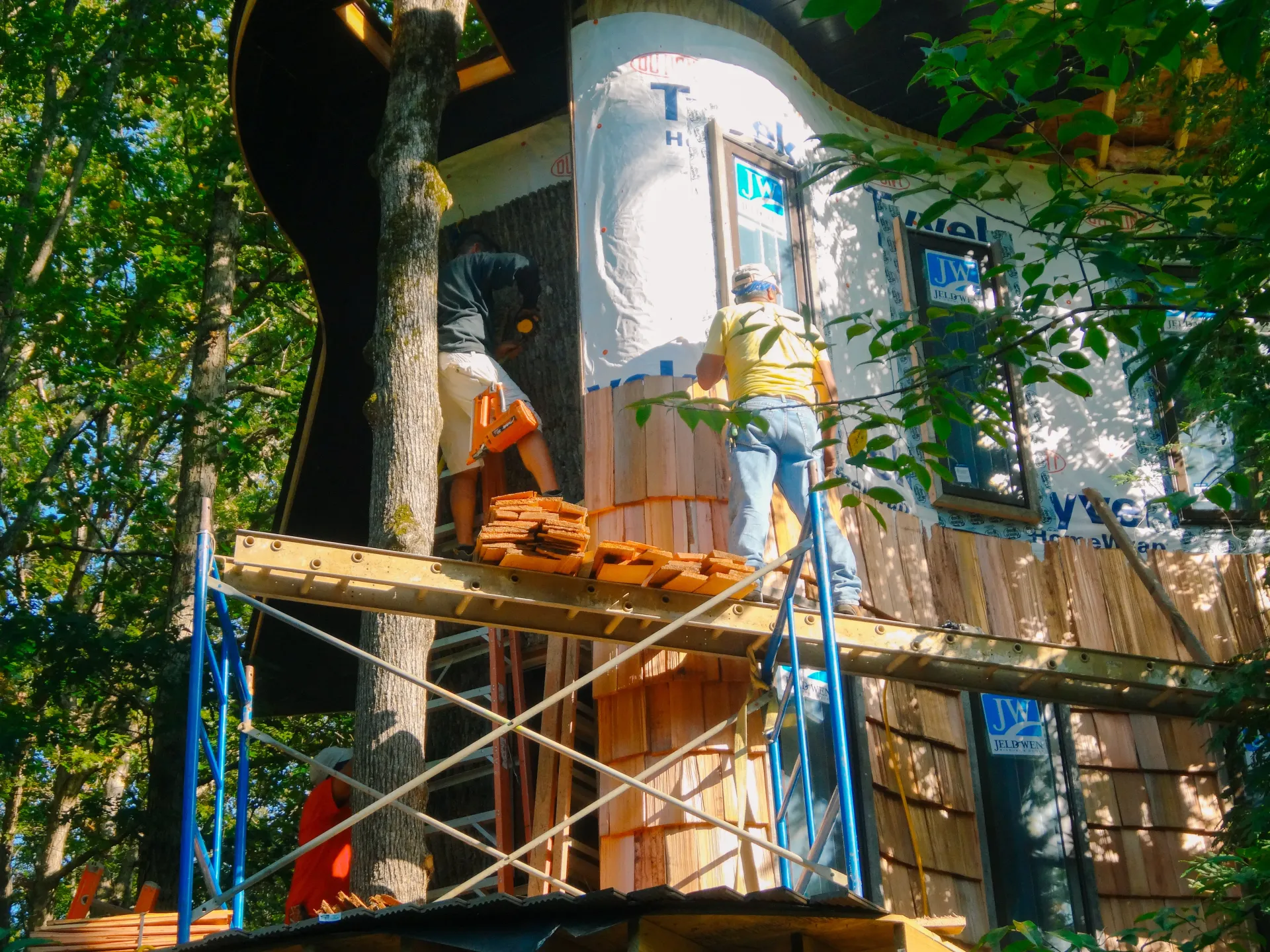 A man is standing on a scaffolding next to a tree house