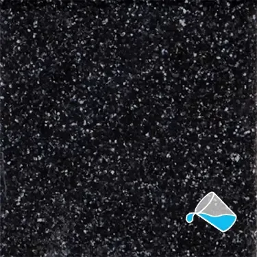A close up of a black tile with a measuring cup on it.