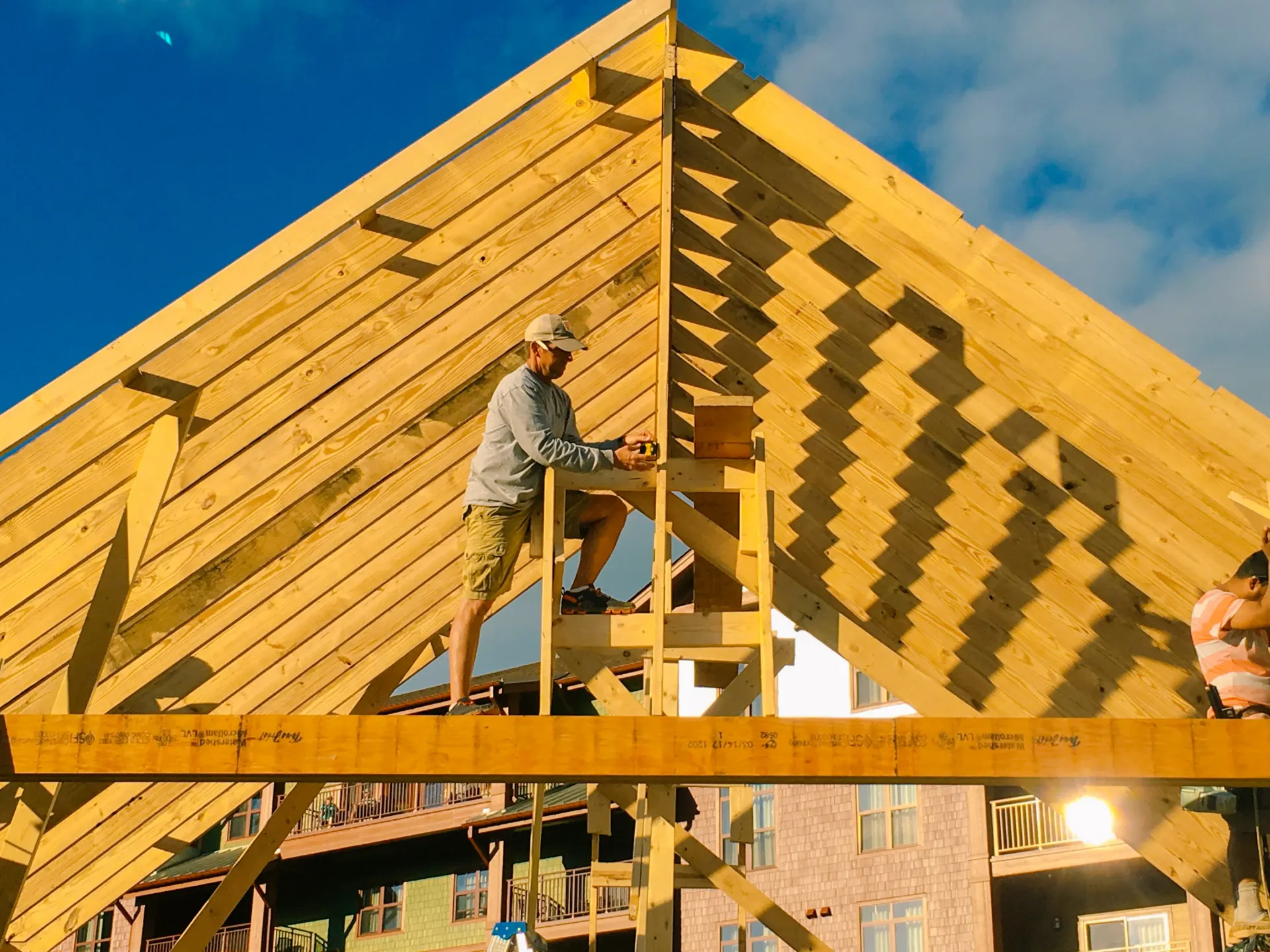A man is sitting on top of a wooden structure.