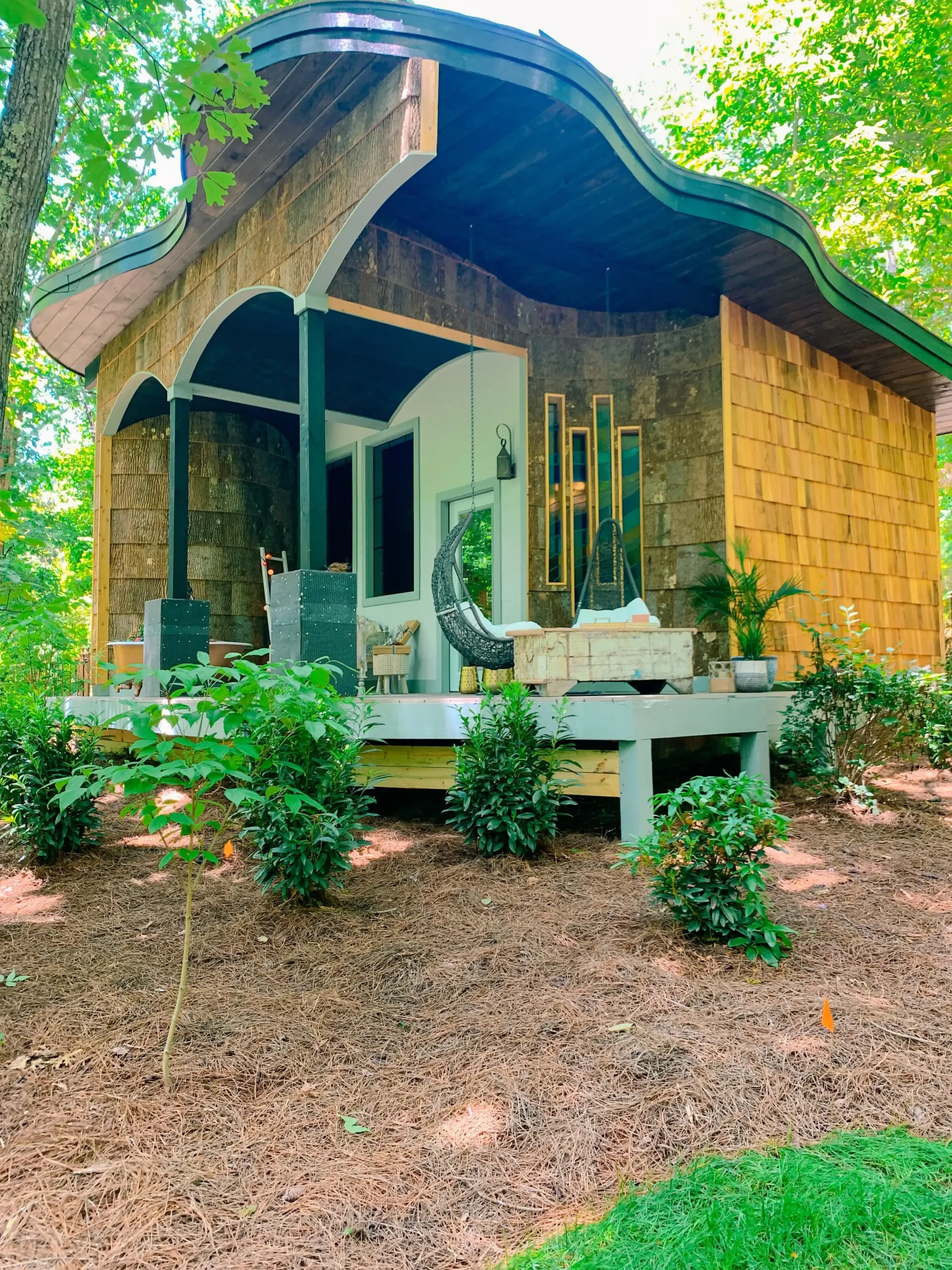 A small house with a porch in the middle of the woods.