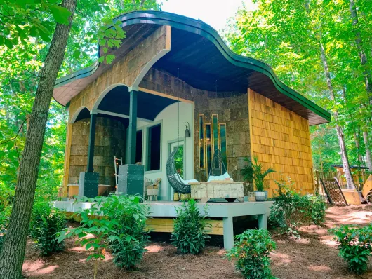 A small house with a porch in the middle of a forest.