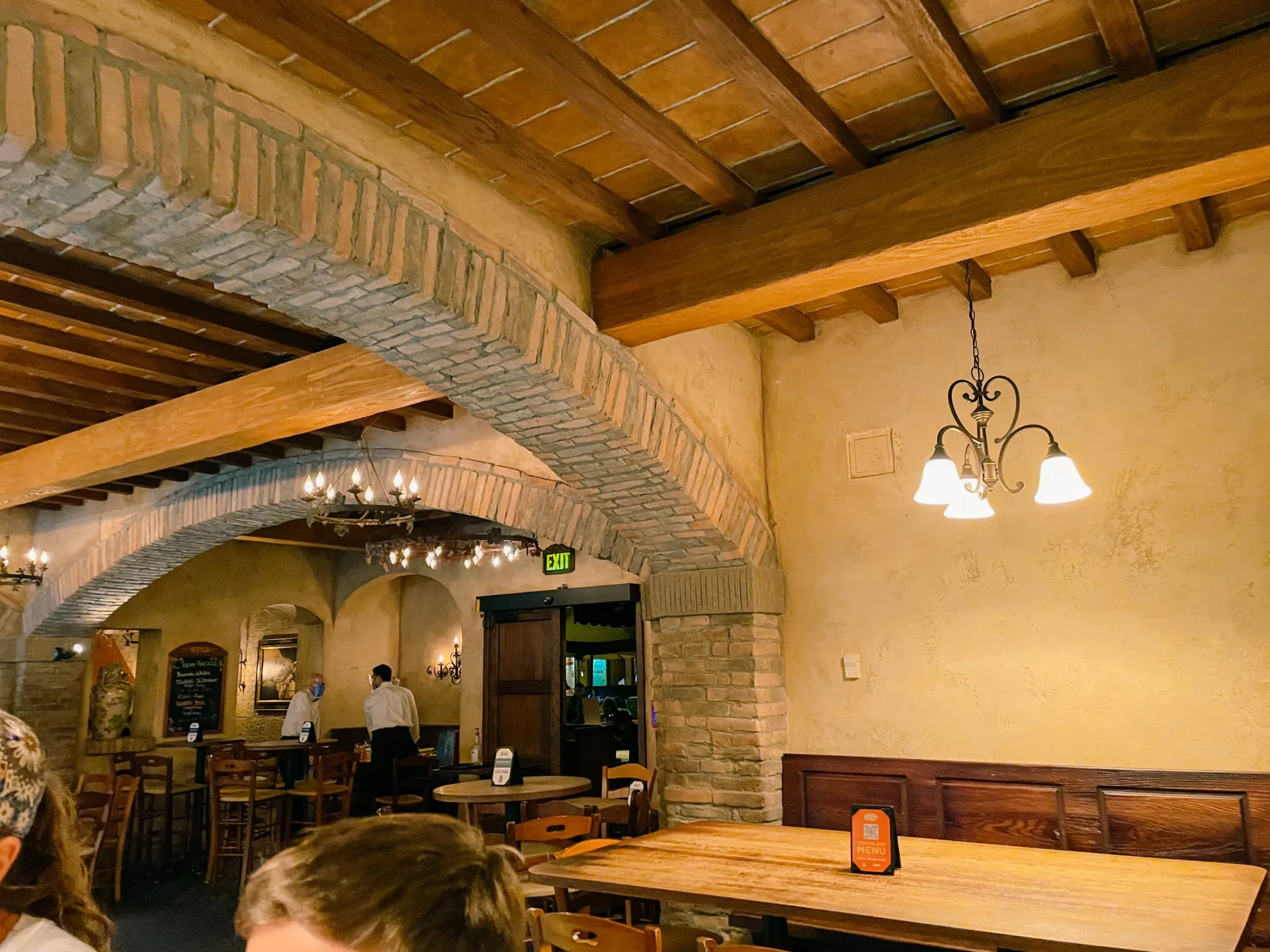 Custom commercial restaurant interior with rustic wood ceilings, arched brick accents, and wrought iron lighting