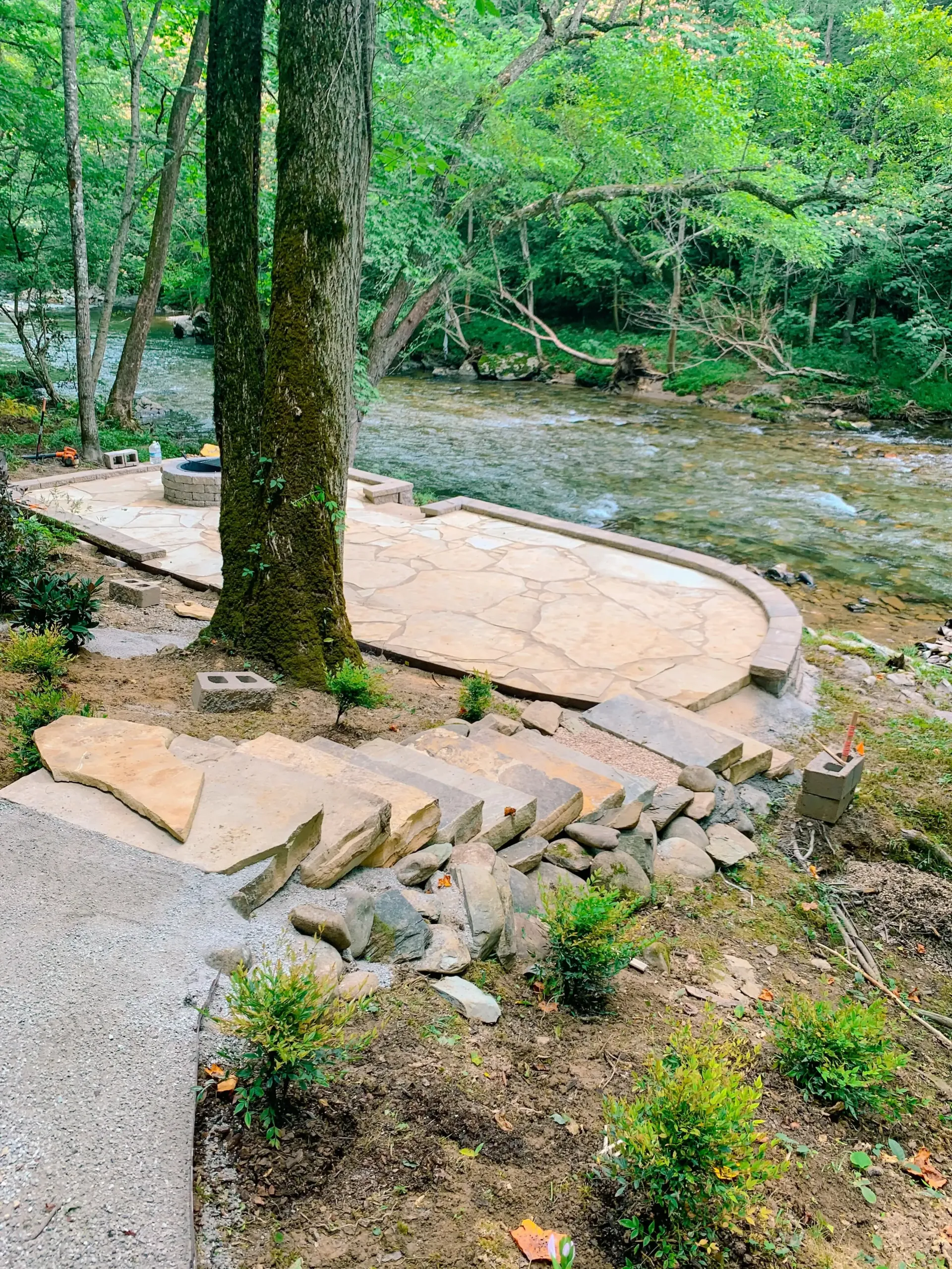 A stone walkway leading to a river in the woods.